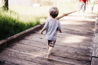 Child running on wooden bridge.