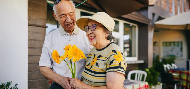 Happy elderly couple holding yellow flowers